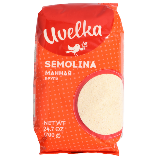 Uvelka semolina in an orange and red bag with white branding, a small white bird, and an oval window showing pale fine grains.